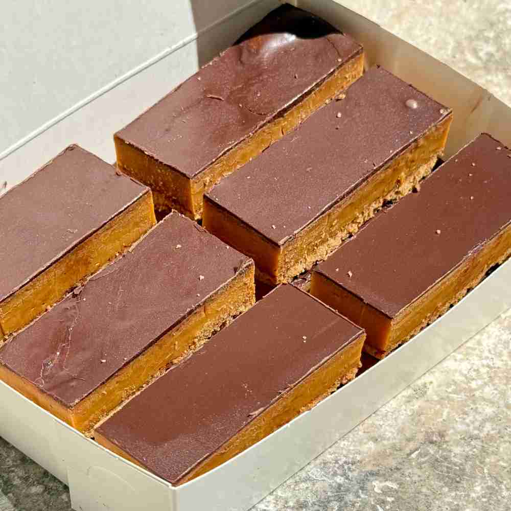 Classic caramel slice with a biscuit base, layered with golden caramel, and topped with a thick layer of chocolate.