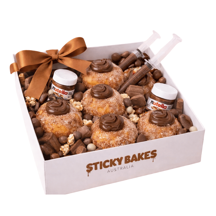 Deluxe box doughnuts filled with Nutella and paired with mini Nutella jars, Nutella syringes, and a mixed selection of chocolates in a white box. 